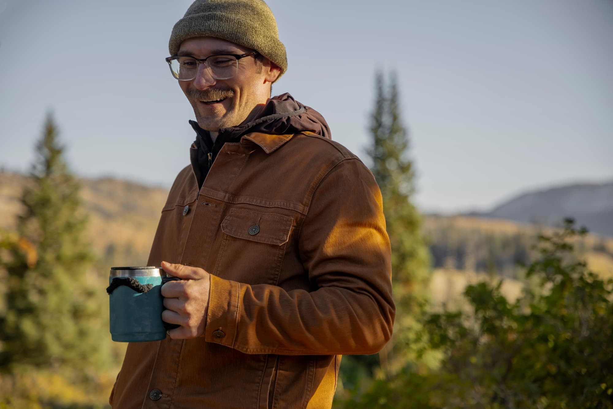 Sean at campsite laughing with coffee mug in hand